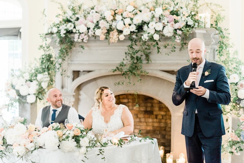 Best Man giving speech in front of fireplace with flowers