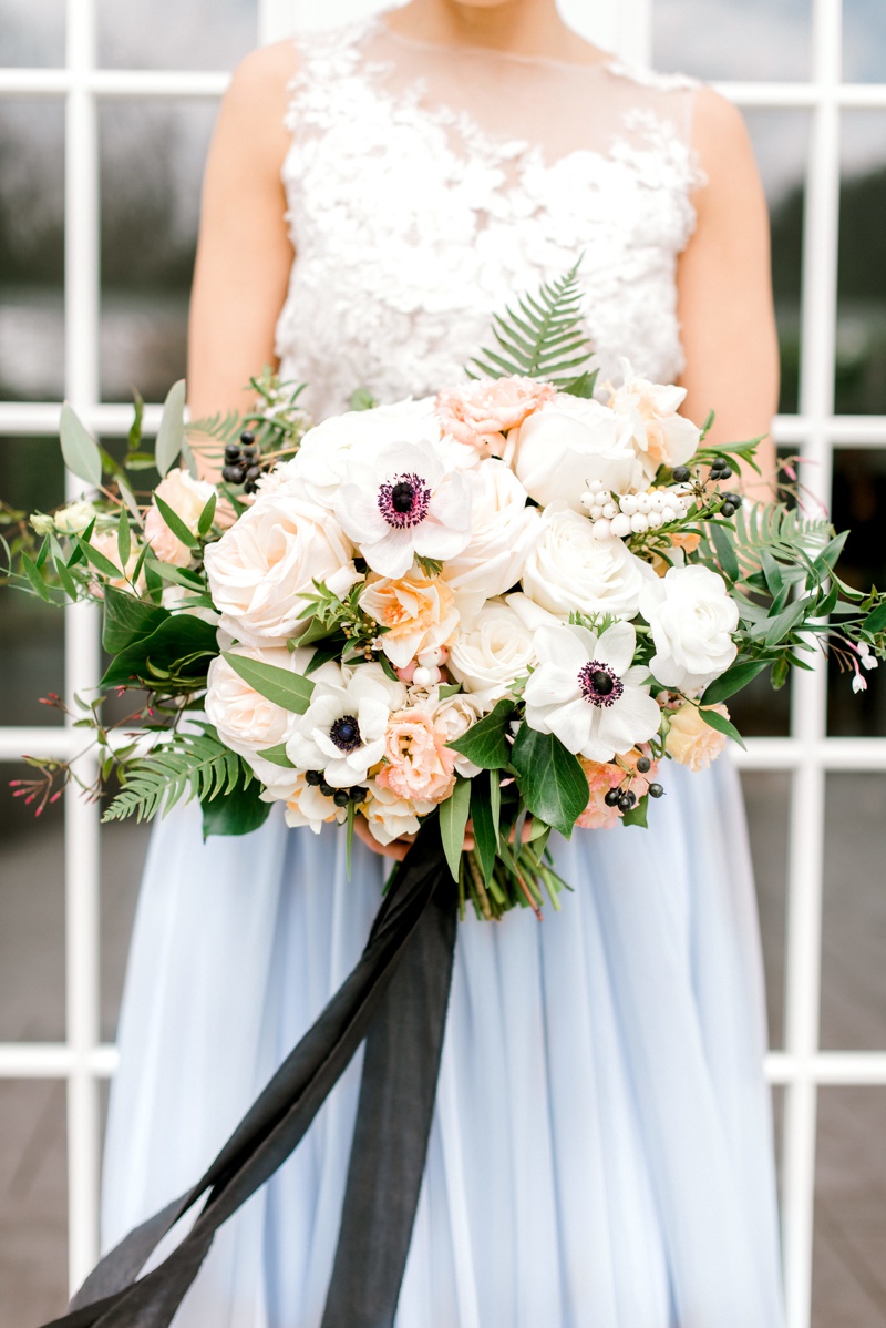 Bride in blue wedding dress holding peach and white bouquet