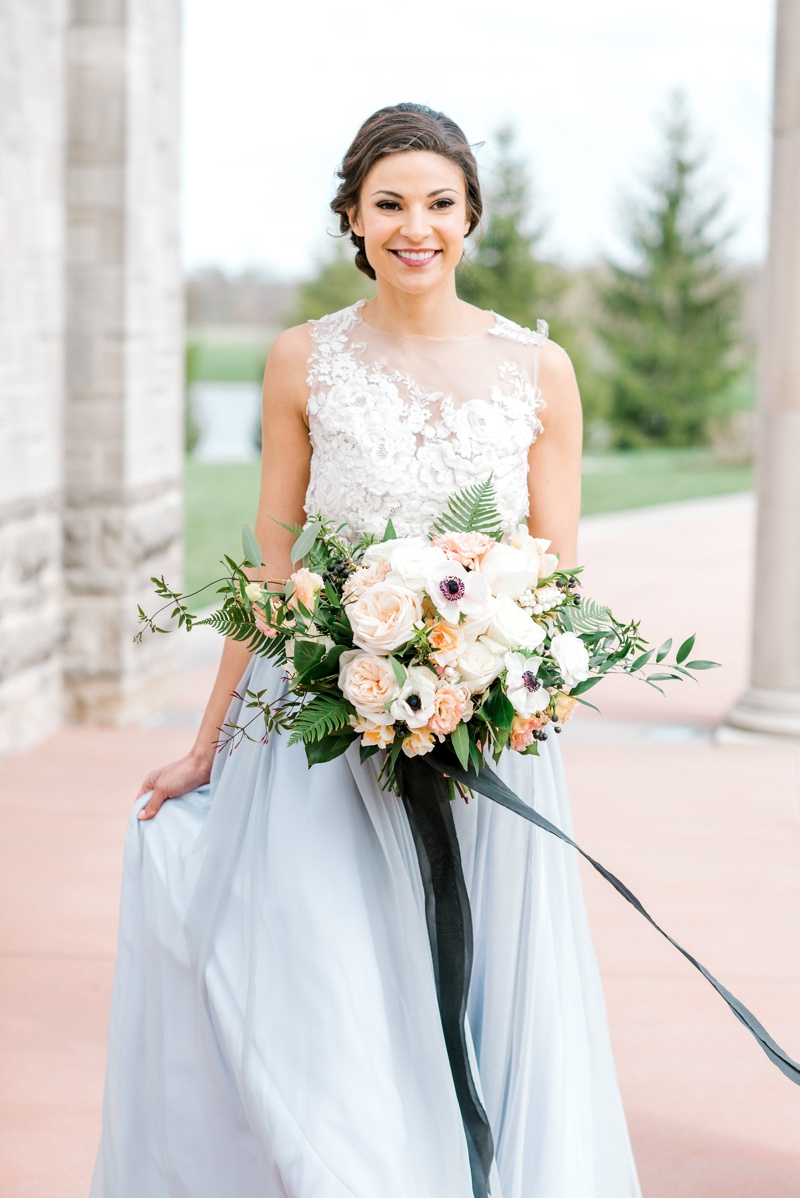 bride with French blue wedding skirt carrying soft peach flowers